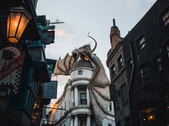 A street scene with a gigantic dragon perched atop a building, surrounded by people and old-style architecture, in the evening light.